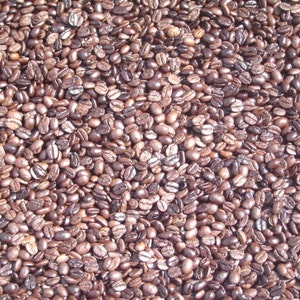 May include: A close-up shot of roasted coffee beans. The beans are a mix of brown and dark brown, with a slightly glossy appearance. The image is tightly packed with beans, showing their texture and shape.