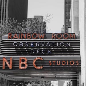 May include: Black and white photograph of the marquee for the Rainbow Room, Observation Deck, and NBC Studios. The words are in neon, with the words "Rainbow Room" and "NBC Studios" in orange, and "Observation Deck" in blue and white.
