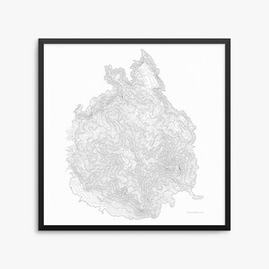 Op de afbeelding: Een ingelijste zwart-wit topografische kaartafdruk. De kaart toont een gedetailleerde contourweergave van een bergketen, met fijne lijnen die hoogteverschillen illustreren. De afdruk is ingesloten in een zwart frame, wat een strakke, moderne esthetiek creëert.