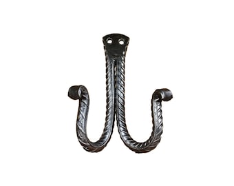 May include: A black metal double hook with a twisted design. The hook is made of wrought iron and has a rustic look.
