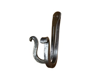 May include: A black metal hook with a unique curved design. The hook is made of forged iron and has a rustic, handmade look.