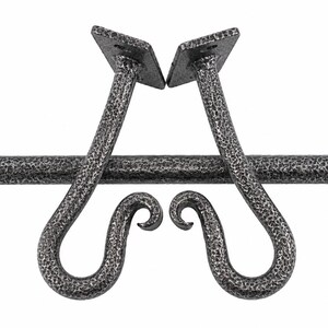 Może przedstawiać: Ciemnoszary metalowy karnisz z dwoma pasującymi wspornikami ściennymi. Każdy wspornik posiada kwadratową płytkę montażową z dwoma otworami na śruby oraz zakrzywiony haczyk w kształcie woluty. Metalowa powierzchnia ma teksturowane, kute wykończenie.