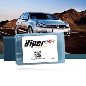 Può includere: Primo piano di un modulo di prestazioni ViperX, un piccolo dispositivo rettangolare con una custodia blu e bianca. Il dispositivo ha un codice QR e il testo "ViperX Performance Module" e "Viperperformance.net". Il dispositivo ha anche un pulsante etichettato come "Reset".