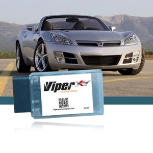 May include: A silver car with a black grille and a red emblem. A blue device with a white label that says "ViperX Performance Module" and a QR code. The text "Viperperformance.net" and "Reset" are also on the label.