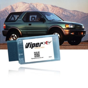 May include: A blue and white Viper X Performance Module with a QR code and the text "Viperperformance.net" and "RESET". The module is in front of a green SUV with a mountain background.