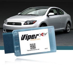 May include: A blue and white Viper Performance Module with a QR code and the text "Viper Performance Module" and "Viperperformance.net". The module is in front of a silver car.