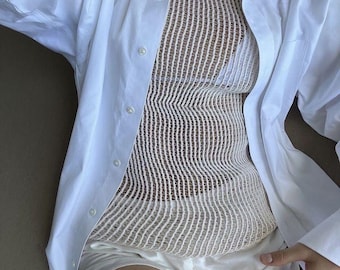 May include: A white button-down shirt with a white mesh tank top underneath. The shirt is unbuttoned and the tank top is visible.