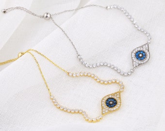 Puede incluir: Dos pulseras ajustables con un dije de ojo turco azul. Una pulsera es plateada y la otra es dorada.