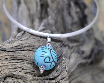 Sterling silver bangle bracelet with turquoise howlite skull bead.