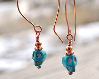 Copper dangle earrings with turquoise howlite skull beads.