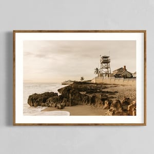 May include: A vintage photograph of a wooden lookout tower on a rocky beach. The tower is on a cliff overlooking the ocean. The photo is in sepia tones.