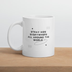 Puede incluir: Taza de cerámica blanca con un gráfico negro que dice "Stray Kids Everywhere All Around The World". El gráfico incluye estrellas y un círculo.