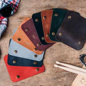 May include: A selection of leather swatches in various colours, including red, brown, black, grey, and green. The swatches are arranged in a fan shape and have small metal rivets around the edges.