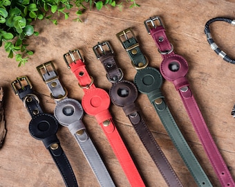 Op de afbeelding: Zes leren hondenhalsbanden in verschillende kleuren, waaronder zwart, grijs, rood, groen, bruin en bordeauxrood. Elke halsband heeft een rond metalen label met een transparant venster.