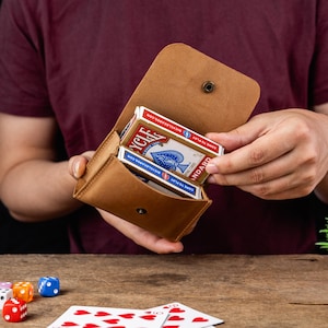 Op de afbeelding: Een beige lederen etui met een drukknoopsluiting met daarin een kaartspel van Bicycle. Het etui is geopend en toont de wit-blauwe kaartendoos met de tekst Bicycle en Standard zichtbaar. Het etui heeft een gladde, matte afwerking.