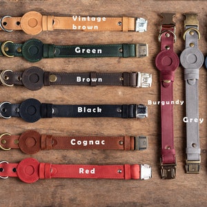 May include: A collection of leather dog collars in various colors, including vintage brown, green, brown, black, cognac, red, burgundy, grey, and blue. Each collar features a circular accent and a metal buckle.