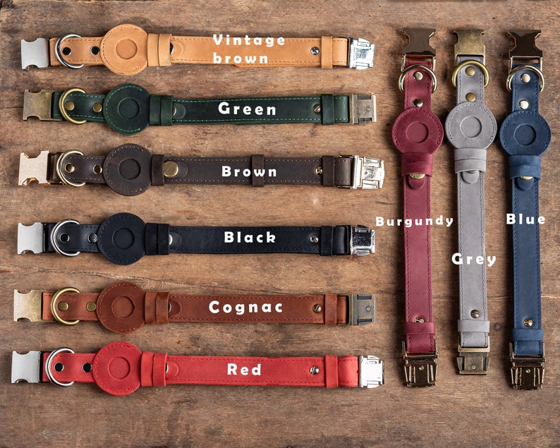 May include: A collection of leather dog collars in various colors, including vintage brown, green, brown, black, cognac, red, burgundy, grey, and blue. Each collar features a circular accent and a metal buckle.