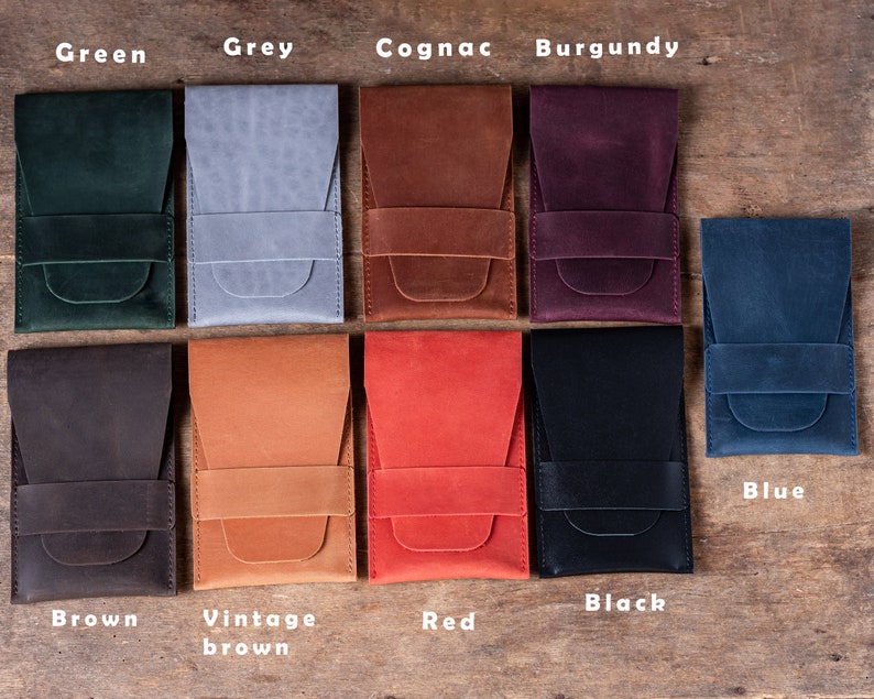 May include: Ten leather phone cases in different colors, including green, grey, cognac, burgundy, blue, brown, vintage brown, red, black. The cases are arranged in two rows of five.