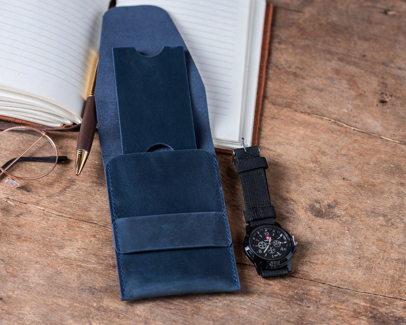 May include: A blue leather wallet with a flap closure and a watch with a black band and a silver face.