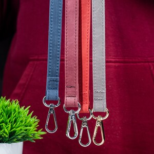 May include: Four different coloured lanyards with gold metal clasps. The lanyards are blue, red, pink, and grey.
