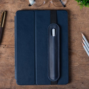 May include: A dark blue tablet case with a built-in stylus holder. The case has a flap that covers the screen and a strap to hold the stylus in place.