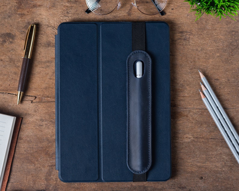 May include: A dark blue tablet case with a built-in stylus holder. The case has a flap that covers the screen and a strap to hold the stylus in place.