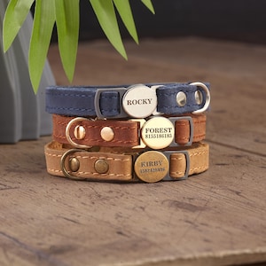 May include: Three stacked leather pet collars in navy blue, medium brown, and light tan. Each collar features a circular metal nameplate engraved with names ROCKY, FOREST, or KIRBY, along with numerical sequences on the brown and tan versions.