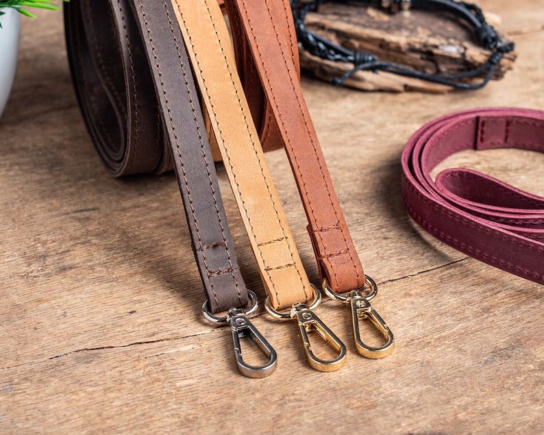 May include: Three leather straps with gold-toned clasps. The straps are brown, tan, and burgundy.