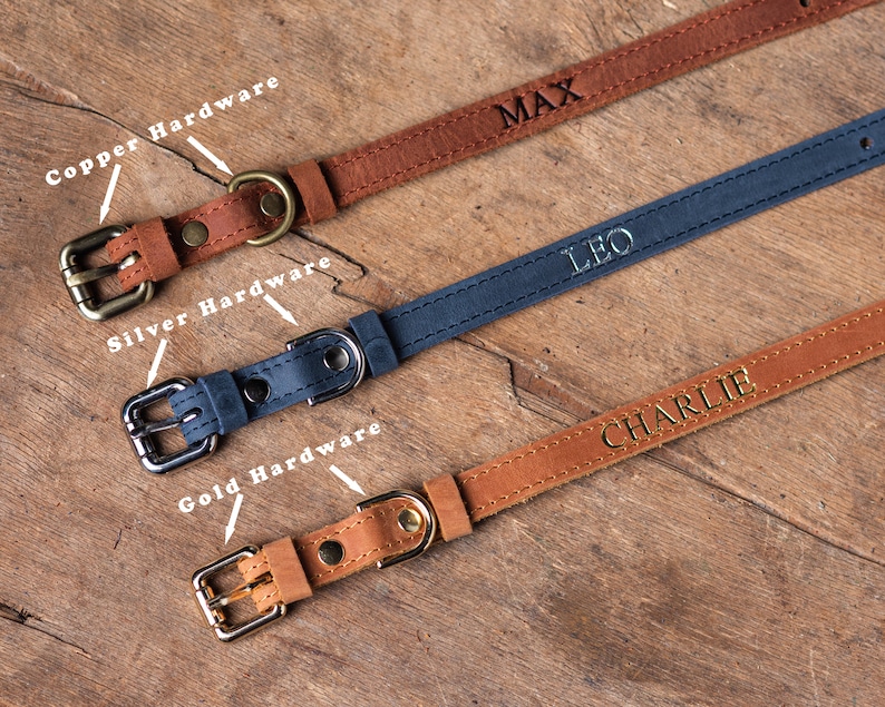 May include: Three leather dog collars with different hardware finishes. The top collar is brown with copper hardware and the name "MAX" engraved on it. The middle collar is blue with silver hardware and the name "LEO" engraved on it. The bottom collar is brown with gold hardware and the name "CHARLIE" engraved on it.
