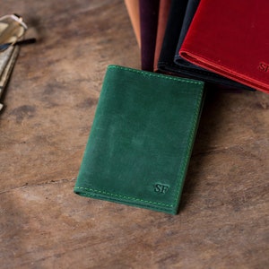 May include: A green leather wallet with the initials "SF" embossed on the front.