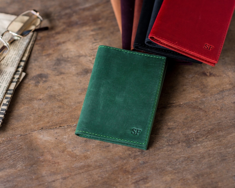 May include: A green leather wallet with the initials "SF" embossed on the front.