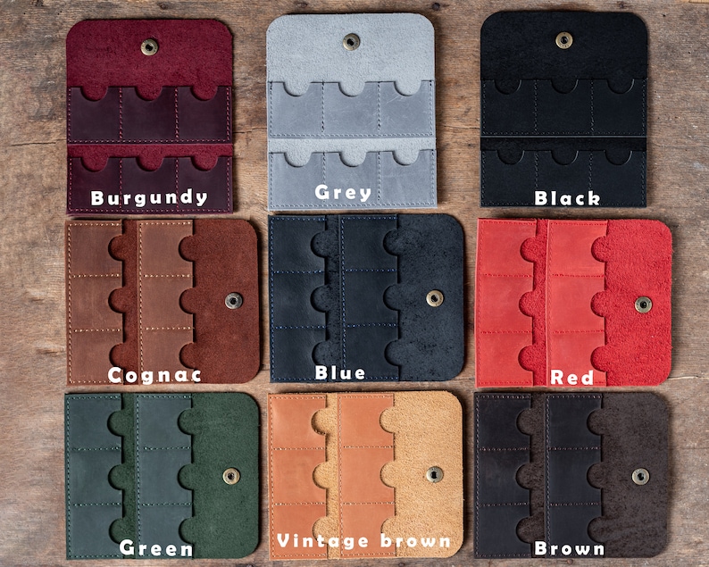 May include: Nine leather card holders in different colours, including burgundy, grey, black, cognac, blue, red, green, vintage brown, and brown. Each holder has six slots for cards.