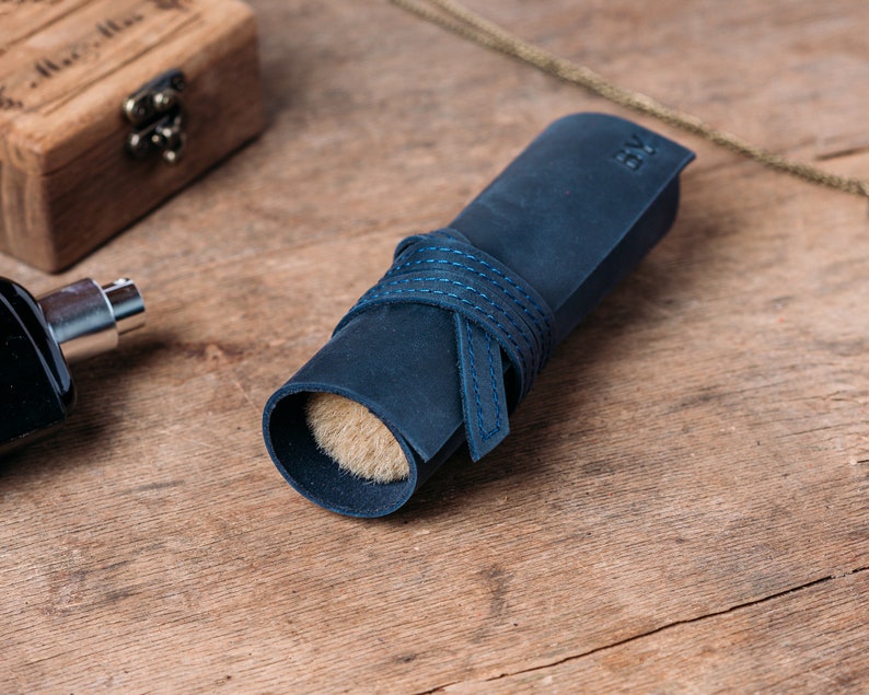 May include: A blue leather roll with a brush inside. The roll is tied with a blue ribbon and has the initials "BV" embossed on the leather.