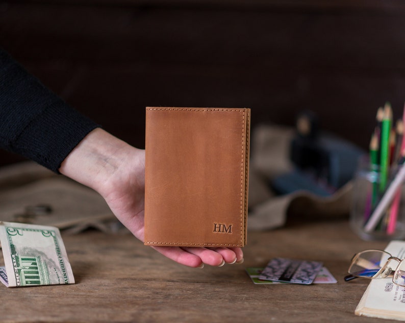 May include: A brown leather passport holder with the initials "HM" embossed on the front.