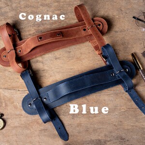May include: Two leather camera straps, one brown and one blue, with adjustable straps and a handle. The straps are labelled "Cognac" and "Blue".