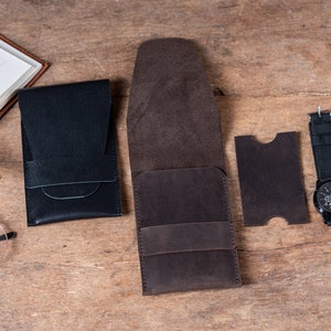 May include: A set of four leather pouches in brown and black. The pouches are made of a soft, supple leather and have a simple, elegant design. The pouches are perfect for storing small items like keys, wallets, or phones.