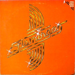 May include: An orange vinyl record cover with a gold logo that says "Flamingos" in a stylized font. The logo is surrounded by gold stars and a gold geometric design.