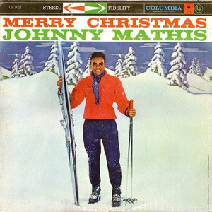 May include: A vintage vinyl record album cover featuring a man in a red sweater and blue trousers holding skis. The album cover is titled "Merry Christmas Johnny Mathis" with the Columbia Records logo in the top right corner.
