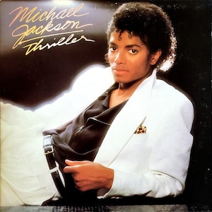 May include: A black and white album cover featuring Michael Jackson in a white jacket and black shirt. The album title "Thriller" is written in gold script.