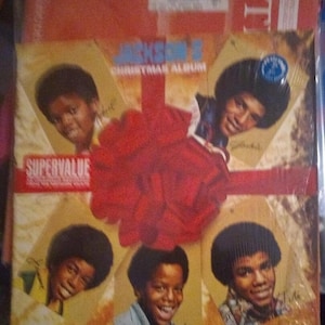 May include: A red and gold Christmas album cover featuring a group of five young men with afros. The album title is "Jackson 5 Christmas Album" and the words "Supervalue" are printed on the cover.