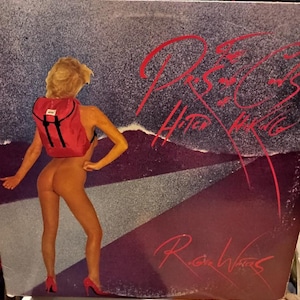 May include: Album cover art showing a nude figure with a red backpack and red high heels. The album title, "R.O.C.S. Hitch Hiking", is written in red script. The background has a purple and grey gradient.