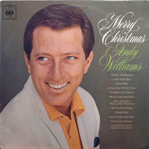 Może przedstawiać: Vintage okładka albumu winylowego z Andym Williamsem. Okładka albumu ma zielone tło z tytułem "Merry Christmas" w eleganckim skrypcie. Williams uśmiecha się, ubrany w białą kurtkę i żółtą koszulę. Tytuły piosenek są wymienione poniżej.