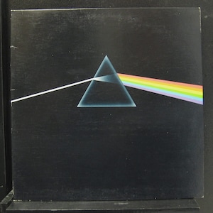 May include: A black vinyl record album cover with a prism and a beam of light. The album cover is for the Pink Floyd album "Dark Side of the Moon".