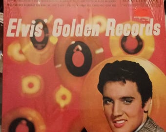 May include: A red vinyl record album cover with the text "Elvis' Golden Records" in white. The cover features a blurred image of Elvis Presley with a gold background and multiple circular shapes.