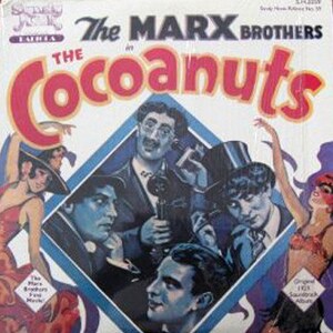 May include: A vintage record album cover featuring a photo of the Marx Brothers in black and white. The album title is "The Cocoanuts" and the text "The Marx Brothers in The Cocoanuts" is printed in white on a blue background. The album cover is a classic example of vintage movie memorabilia.