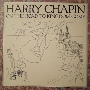 Könnte beinhalten: Ein Schallplattencover für Harry Chapins On the Road to Kingdom Come mit beigem Hintergrund und schwarzer Strichzeichnung eines Gesichts und einer Küstenburg. Das Cover enthält eine handschriftliche Widmung To Jeanne Hope to meet you someday sowie eine Unterschrift.