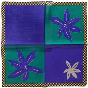 May include: A square, folded textile with a checkered border. The design features four quadrants: two blue with horizontal lines, and two teal with purple floral designs. A white floral design is in the lower right quadrant.