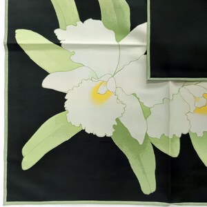 Puede incluir: Pa&ntilde;uelo cuadrado en blanco y negro con un dise&ntilde;o de orqu&iacute;deas. Las orqu&iacute;deas son blancas con centros amarillos y hojas verdes. El pa&ntilde;uelo tiene un borde verde. Mide aproximadamente 60 cm x 60 cm.