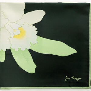 Puede incluir: Pa&ntilde;uelo cuadrado de seda con un gran dise&ntilde;o de orqu&iacute;dea blanca y amarilla sobre fondo negro. La orqu&iacute;dea tiene hojas verde claro y un borde verde claro. La firma "Jim Thompson" est&aacute; en la esquina inferior derecha.