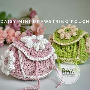 以下が含まれることがあります： かぎ針編みのデイジーミニ巾着ポーチが2つ。1つは白のアクセントが付いたピンク色、もう1つはベージュのアクセントが付いた緑色です。ポーチにはフラップに花があり、「DAISY MINI DRAWSTRING POUCH」と「CROCHET PATTERN BY VIVMADE」と書かれています。